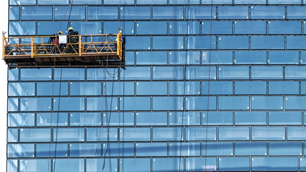 Workers, standing in the ropes installation basket, wash skyscraper windows from the outside