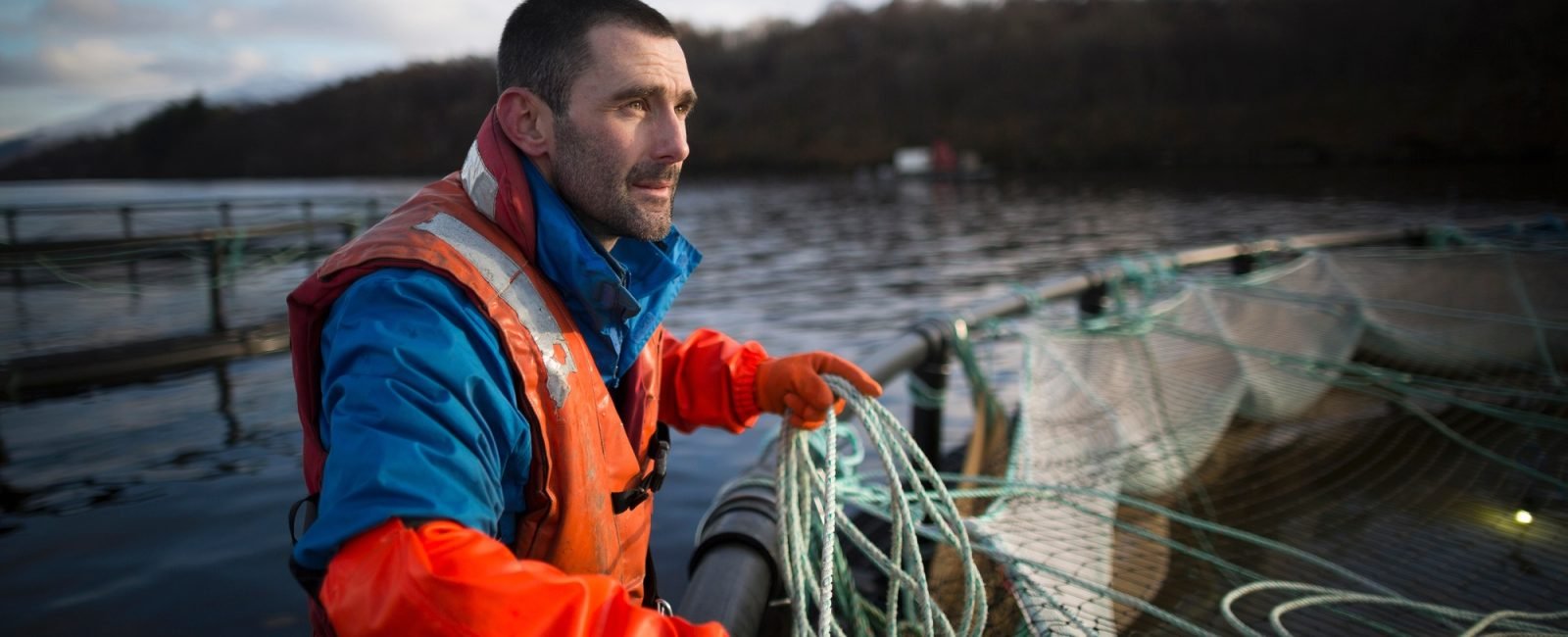 Worker on salmon farm in rural lake